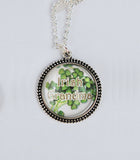 Pendant of antique silver bezel set sweet shamrocks captured under a dome of crystal clear glass with the words "Irish Grandma."